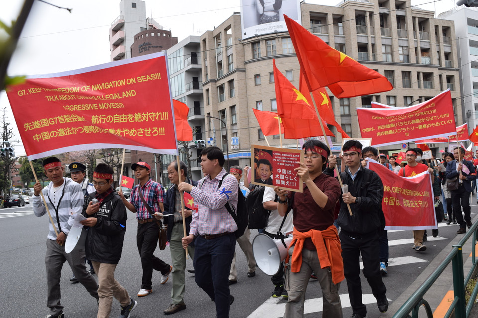 Những người tham gia tuần hành giương cao quốc kỳ Việt Nam, các biểu ngữ với các nội dung yêu cầu Trung Quốc tuân thủ luật pháp quốc tế, tôn trọng chủ quyền các nước láng giềng. (Nguồn: Tri Phương/Vietnam+)