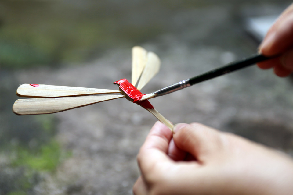 Để tạo được ấn tượng, những con chuồn chuồn được sơn và trang trí lên rất nhiều hoa văn, họa tiết khác nhau; công đoạn này, người thợ rất cần sự khéo léo. (Ảnh: Doãn Đức/Vietnam+)