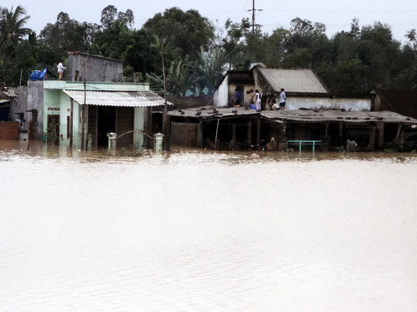 Nhiều người dân vùng ngập nước ở huyện Sơn Tịnh, Quảng Ngãi phải lên mái nhà tránh lũ. (Ảnh: Thanh Long/TTXVN)