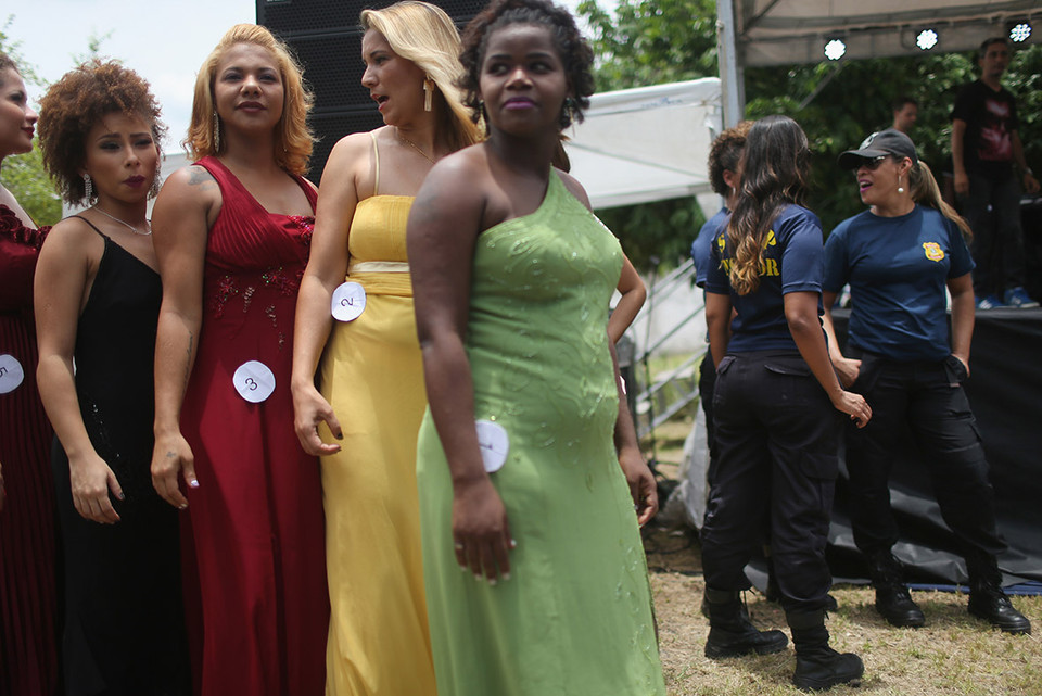 Các thí sinh mặc trang phục dạ hội, đứng bên cạnh là các quản ngục. (Nguồn: ibtimes)