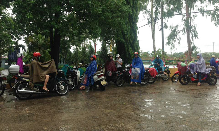 Do sân trước điểm thi của Trung tâm giáo dục thường xuyên Thanh Trì không có mái che, nên tất cả các phụ huynh đều phải mặc áo mưa. (Ảnh: Sơn Bách/Vietnam+)