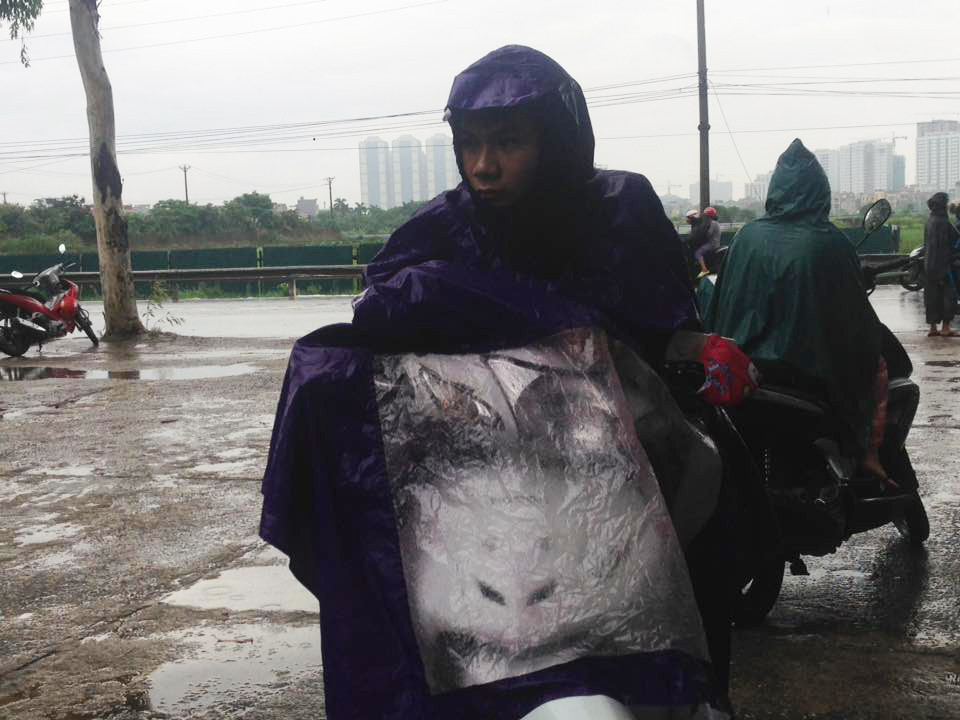 Khi các thí sinh vội vàng vào trong trường để làm thủ tục thì phía ngoài cổng, các phụ huynh vẫn kiên nhẫn đội mưa đứng đợi. (Ảnh: Sơn Bách/Vietnam+)