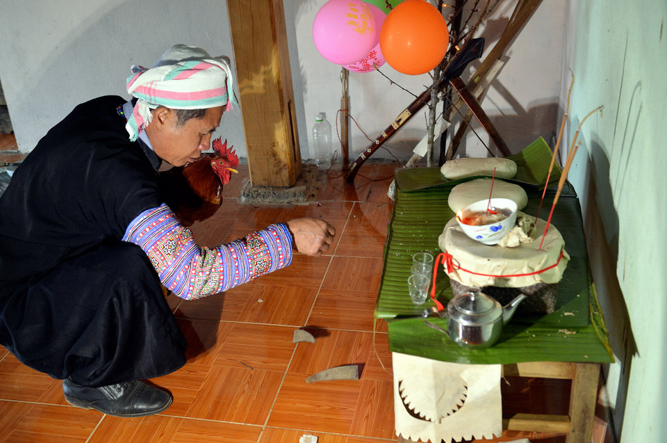 Thầy cúng làm nghi lễ xin âm dương, hai miếng sừng úp là thổ địa đã chứng giám cho gia chủ được thịt gà để hành lễ. (Ảnh: Thanh Hà/TTXVN) 