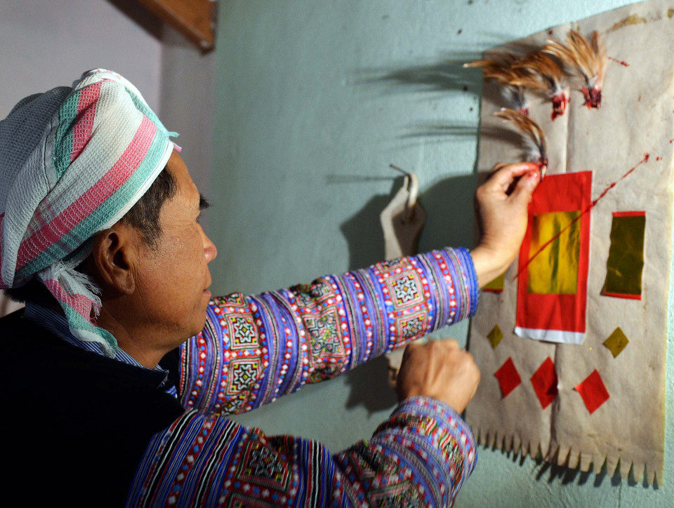  Cắt tiết gà xong, thầy cúng nhổ năm nhúm lông gà nhúng tiết để đính lên ban thờ vừa được thay mới. (Ảnh: Thanh Hà/TTXVN) 