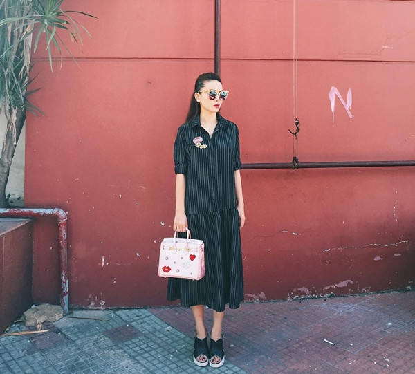 Đầm sơmi kẻ tăm và sandals là combo luôn khiến Yến Trang mê mẩn. Nữ ca sỹ kết hợp bộ cánh này cùng túi xách hồng phấn đính logo và mắt kính cực 'ngầu.'