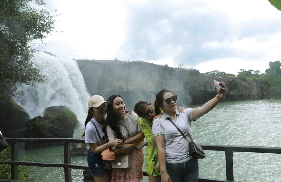 Du khách tự chụp ảnh kỷ niệm khi đến thác Dray Nur. (Ảnh: Vũ Sinh/TTXVN)