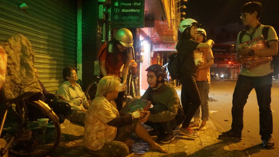 Gần 11 giờ đêm, các bạn sinh viên trường Đại học Kiến Trúc Thành phố Hồ Chí Minh đi tìm những người vô gia cư để phát cháo và quà Tết. (Ảnh: Lưu Văn Đạt/Vietnam+)