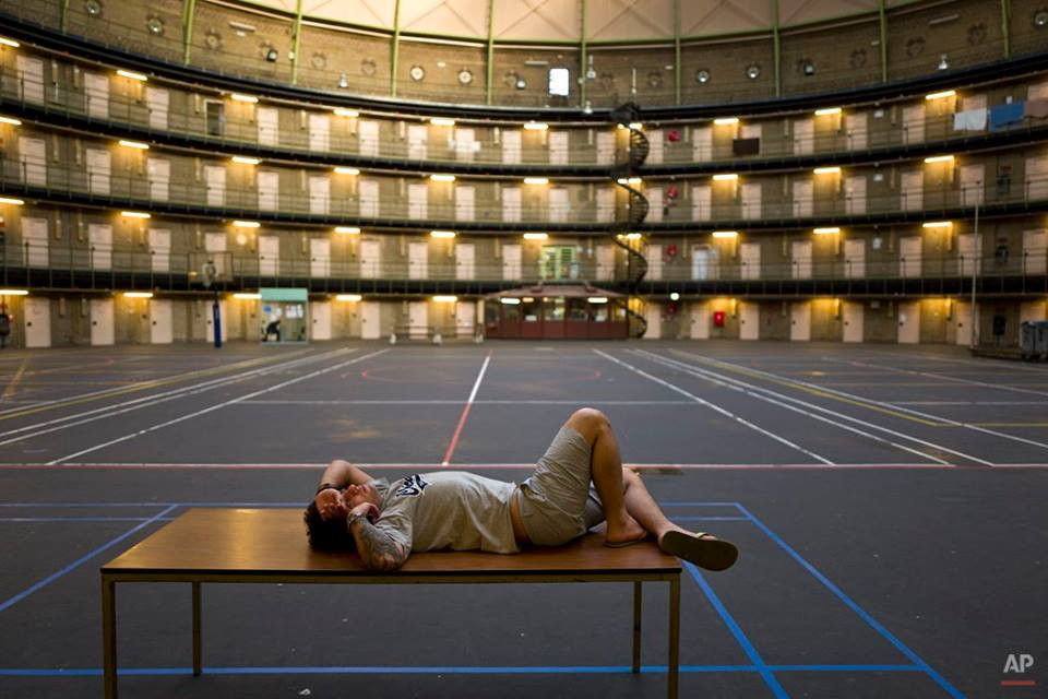 Reda Ehsan (25 tuổi), người tị nạn từ Iran, đang nằm trên cái bàn đặt trong nơi từng là nhà tù De Koepel ở Hà Lan. Nhà tù này giờ được sử dụng như một trung tâm hỗ trợ người tị nạn. (Nguồn: AP)
