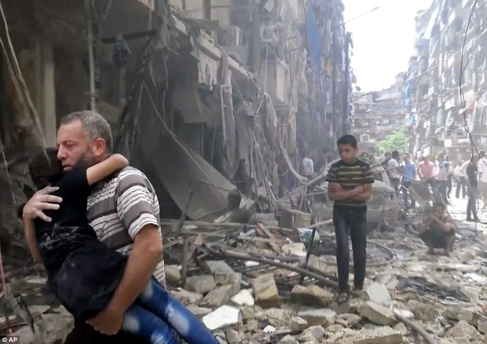 Một người bố bế con tới nơi an toàn. Trong vòng 24 giờ qua, đã có ít nhất 61 người thiệt mạng, bao gồm cả bác sỹ và trẻ nhỏ đang điều trị tại bệnh viện. (Nguồn: dailymail)