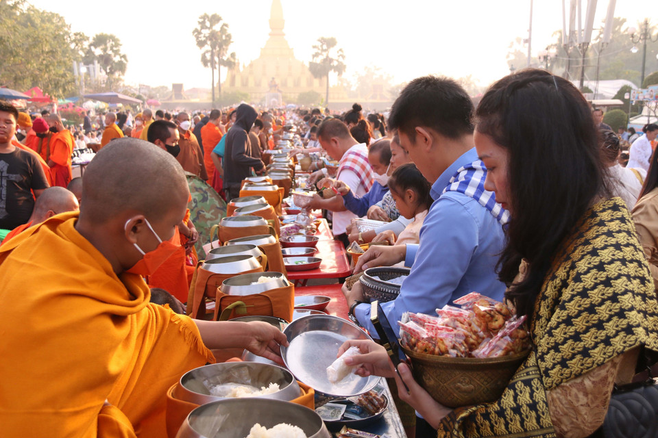 Người dân Lào thực hiện nghi lễ Xaybath (Cúng dường), một trong những nghi lễ được thực hiện trong suốt hai ngày lễ Thatluang. (Ảnh: Phạm Kiên-Bá Thành/TTXVN)