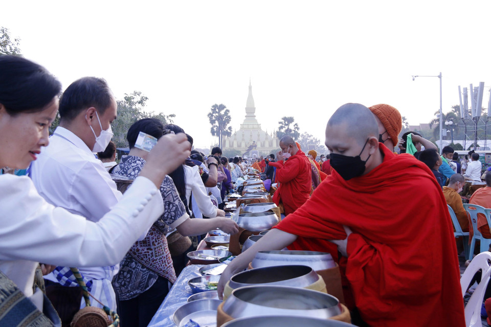 Người dân Lào thực hiện nghi lễ Xaybath (Cúng dường), một trong những nghi lễ được thực hiện trong suốt hai ngày lễ Thatluang. (Ảnh: Phạm Kiên-Bá Thành/TTXVN)