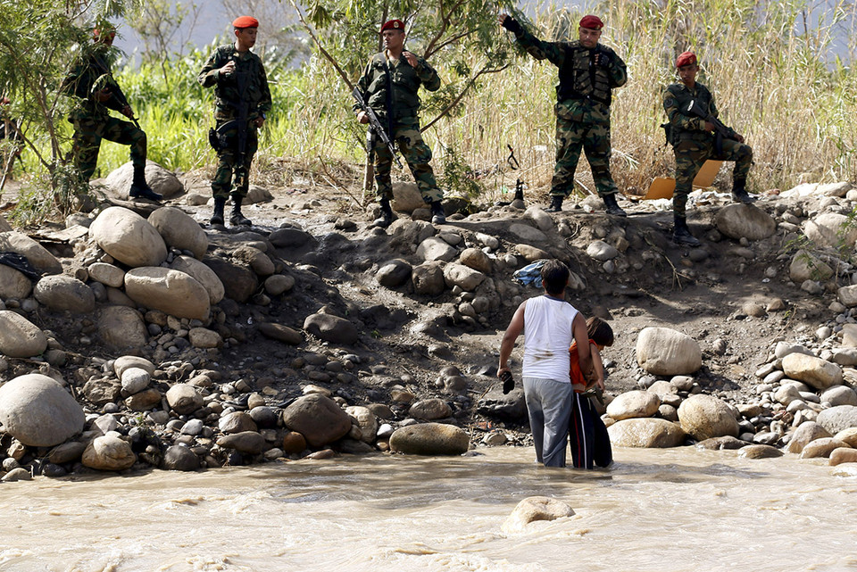 Binh sỹ Venezuela không cho phép hai cha con đang đứng trên sông Tachira được vào địa phận của quốc gia này. (nguồn: Reuters)