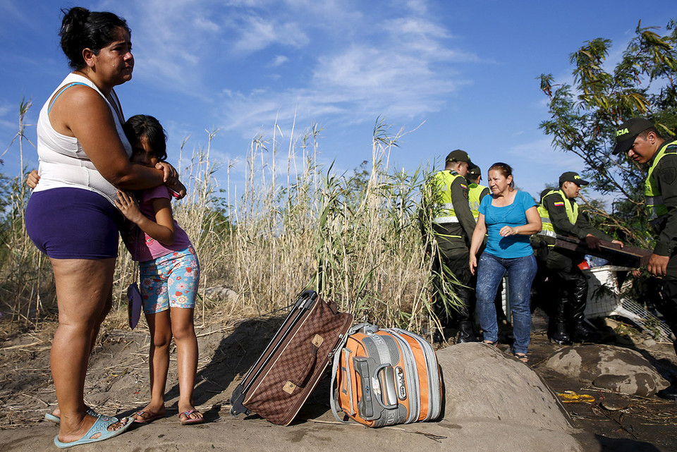 Người phụ nữ khóc trong khi ôm con gái, trước khi gửi cô bé về Colombia. (Nguồn: Reuters)