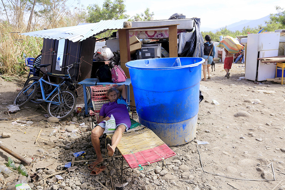 Một bà lão Colombia xuất cảnh khỏi Venezuela đang nằm nghỉ bên tài sản của mình ở sông Tachira. (Nguồn: Reuters)