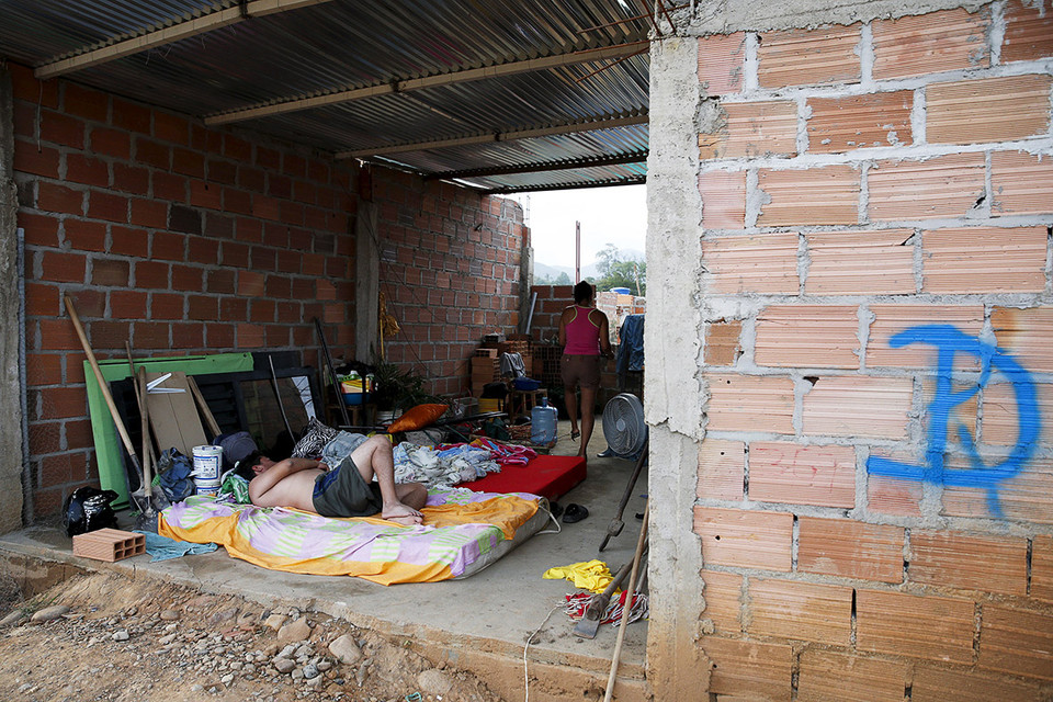 Người đàn ông đang ngủ trên đệm trong căn nhà đã bị phá dỡ một phần. Căn nhà đã bị đánh dấu 'D' để phá hủy. (Nguồn: Reuters)