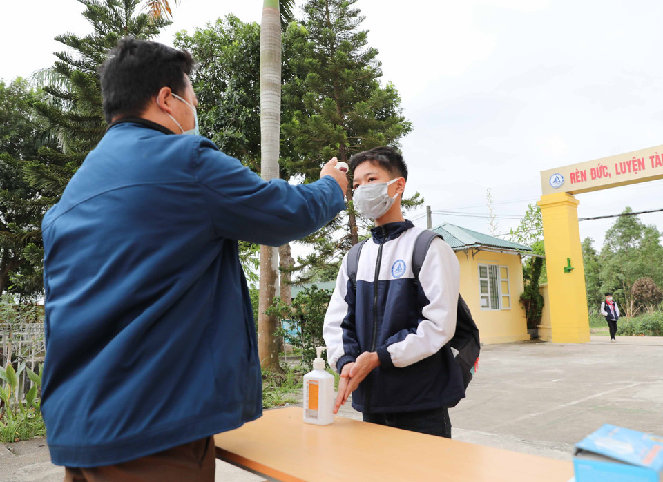 Đo thân nhiệt, sát khuẩn tay cho học sinh khi tới trường. (Ảnh: Thanh Tùng/TTXVN)