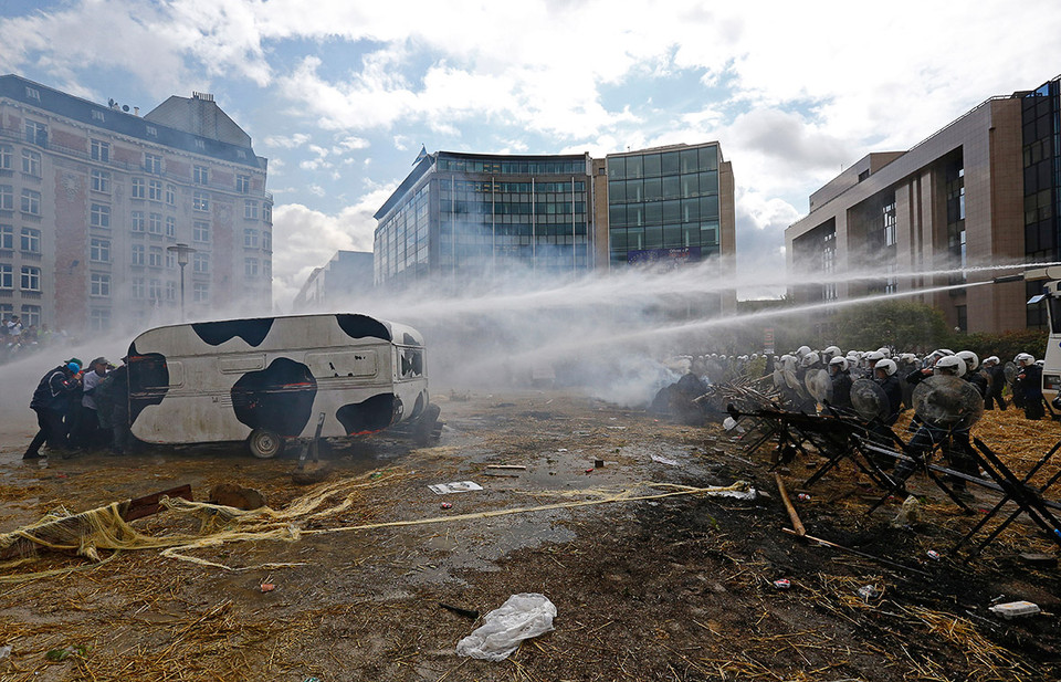 Những người nông dân nấp sau xe tải khi cảnh sát dùng súng nước để giải tán đám đông. (Nguồn: Reuters)