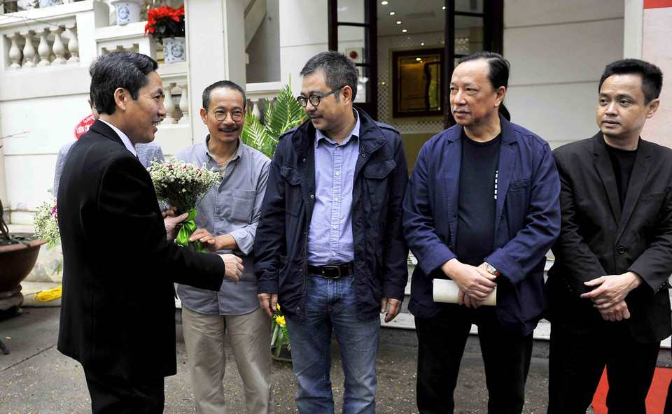 Nhà báo Thuận Hữu – Tổng Biên tập Báo Nhân Dân tặng hoa cho họa sĩ tham dự triển lãm. (Ảnh: Ngọc Tùng/Vietnam+)