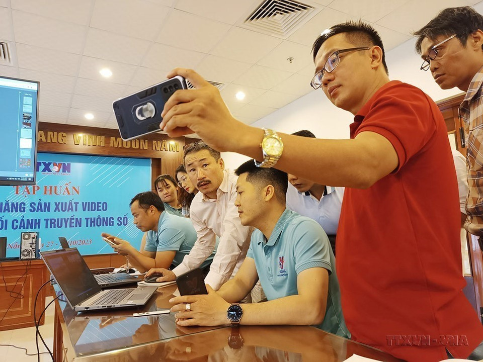 Phóng viên Thông tấn xã Việt Nam trao đổi về cách dựng video bằng điện thoại di động tại lớp “Kỹ năng sản xuất video trong bối cảnh truyền thông số” được tổ chức ở Đà Nẵng. (Ảnh: TTXVN)