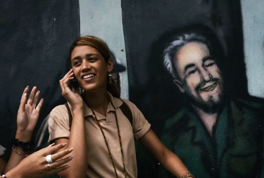 Nữ sinh Cuba đứng bên cạnh bức họa graffiti Fidel Castro ở Caracas. (Nguồn: RT) 