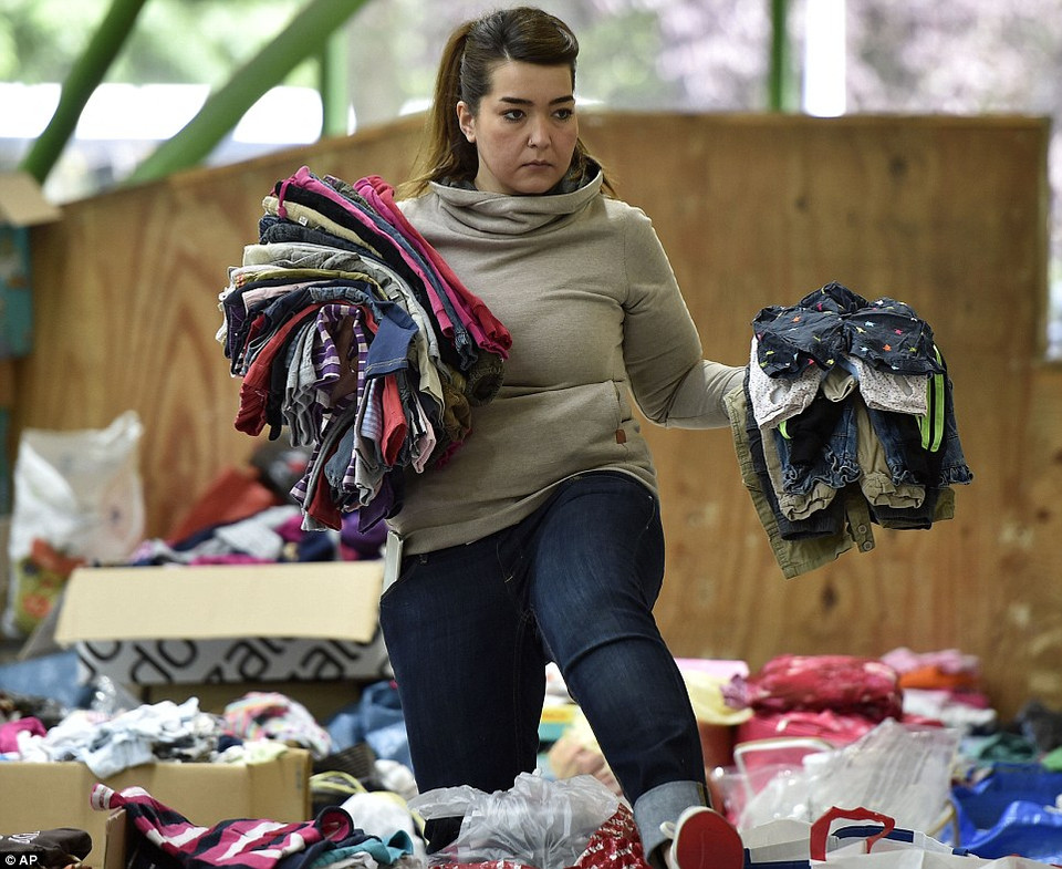 Một người tình nguyện phân loại quần áo trẻ em được quyên góp ở Dortmund (Đức), chuẩn bị cho hàng trăm người nhập cư sắp tới đây. (Nguồn: Dailymail)