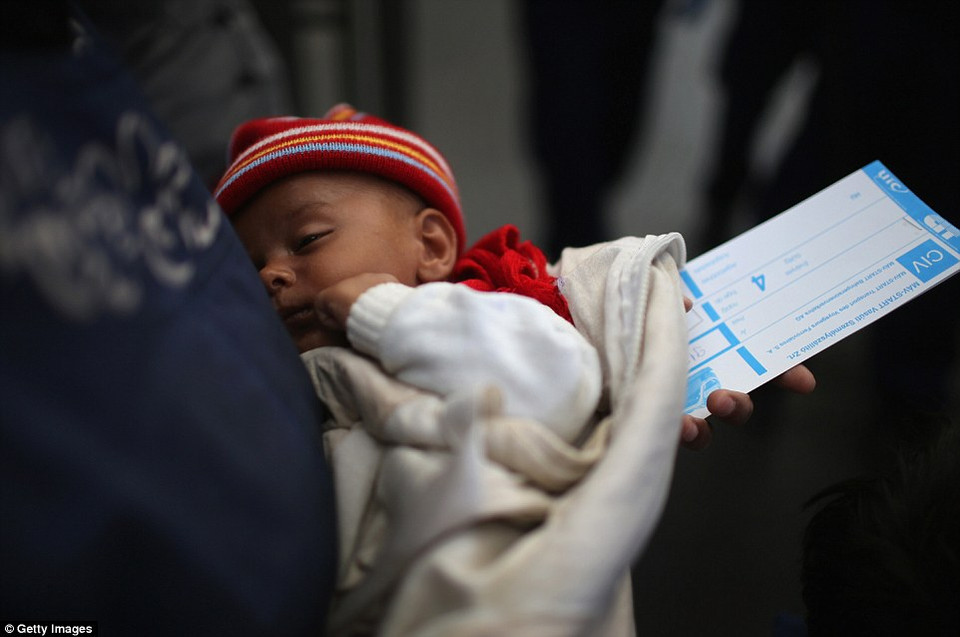 Một bà mẹ vừa bế con vừa cầm vé chờ tàu ở Budapest để tới Áo. (Nguồn: Dailymail)