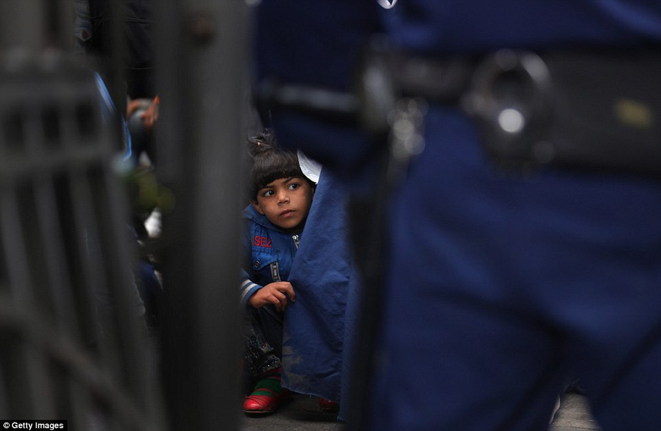 Một em bé bám chặt chặt mẹ khi làm thủ tục lên tàu ở nhà ga Keleti. (Nguồn: Dailymail)