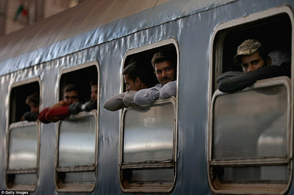 Những người di cư tựa trên cửa sổ xe lửa. (nguồn: Dailymail)