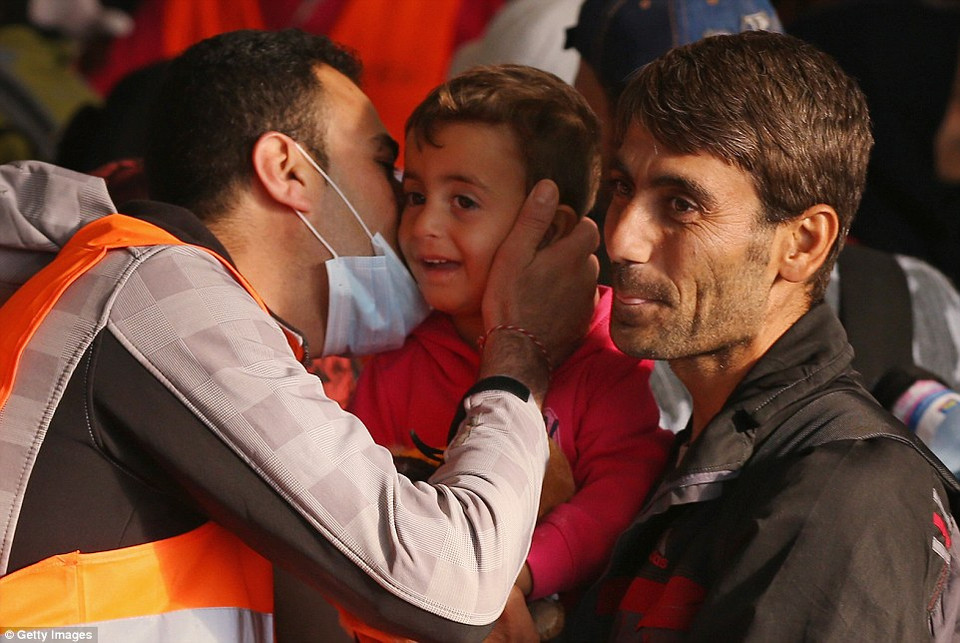 Một người Đức hôn lên má em bé nhập cư. (Nguồn: Dailymail)