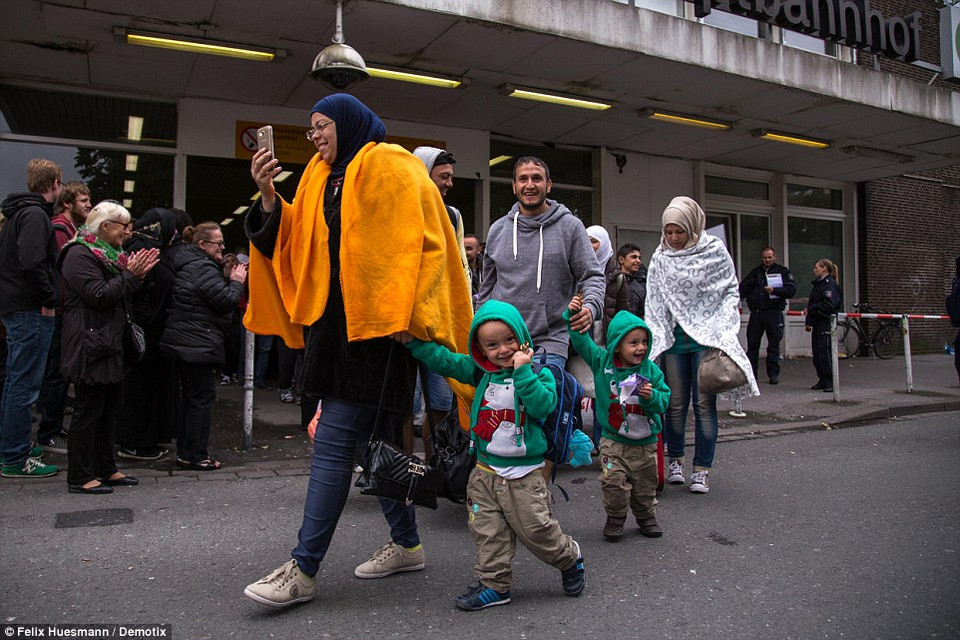 Bà mẹ dẫn 2 con nhỏ ra khỏi nhà ga Dortmund trong tiếng vỗ tay đón chào của người Đức. (Nguồn: Dailymail)