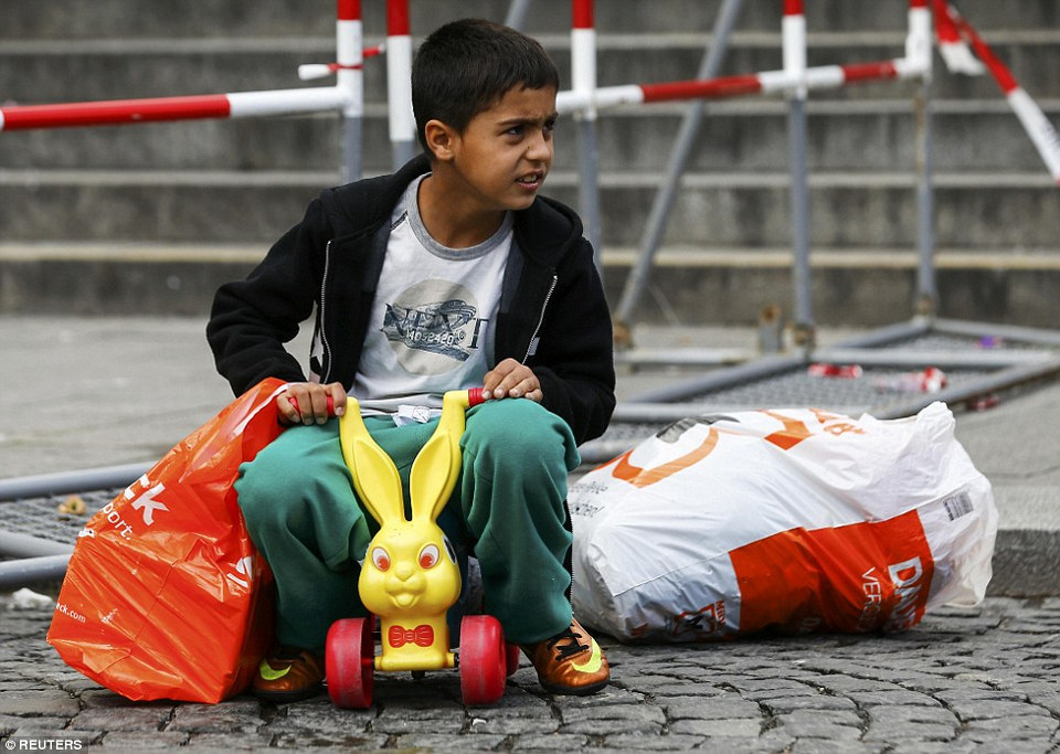 Một em bé ngồi đợi trên chiếc xe đồ chơi trong khi gia đình em chuẩn bị cho hành trình tiếp theo từ nhà ga trung tâm Munich để tới các trại tập trung dành cho người tị nạn trên khắp nước Đức. (Nguồn: Dailymail)