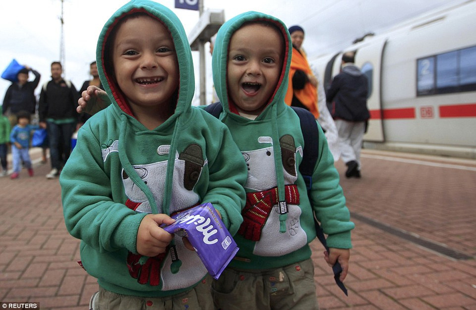 Hai em bé cầm chocolate cười tươi trước ống kính khi tới Dortmund (Đức). (Nguồn: Dailymail)