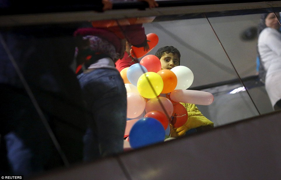 Bé trai nhận được chùm bóng bay khi em tới thang máy để đăng ký tị nạn sau khi tới Frankfurt. (Nguồn: Dailymail)