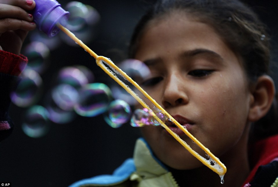 Một em bé thổi bong bóng khi chờ những người tị nạn khác ở nhà ga Keleti. (Nguồn: Dailymail)