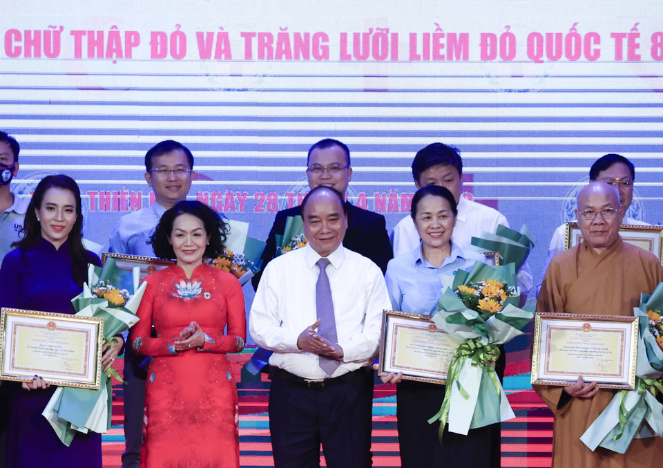 Chủ tịch nước Nguyễn Xuân Phúc tặng hoa cho các nhà tài trợ. (Ảnh: Thống Nhất/TTXVN)