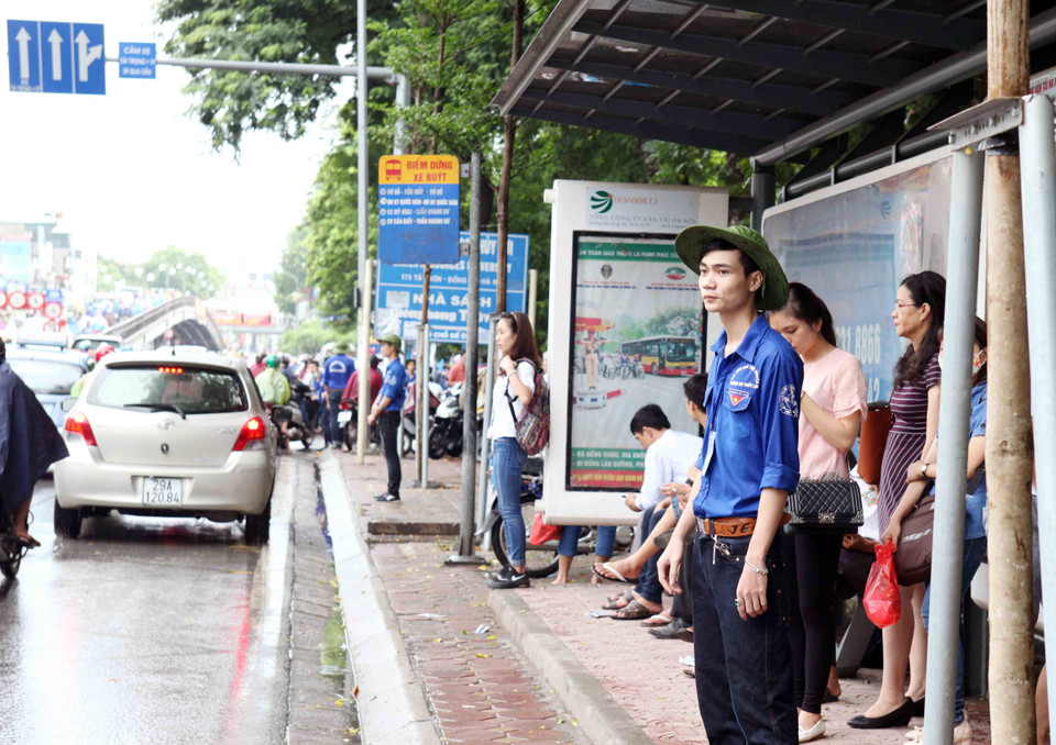 Lực lượng sinh viên tình nguyện, cảnh sát giao thông, cảnh sát trật tự đội mưa đảm bảo giao thông và hướng dẫn các thí sinh làm vào thủ tục thi. (Ảnh: Doãn Đức/Vietnam+)