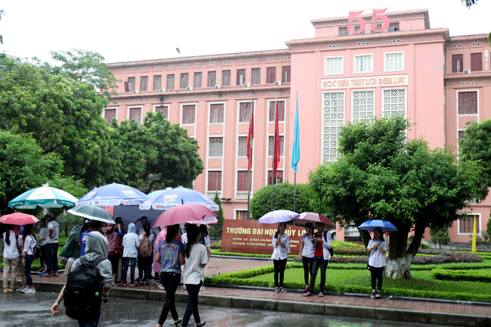 Lực lượng sinh viên tình nguyện, cảnh sát giao thông, cảnh sát trật tự đội mưa đảm bảo giao thông và hướng dẫn các thí sinh làm vào thủ tục thi. (Ảnh: Doãn Đức/Vietnam+)