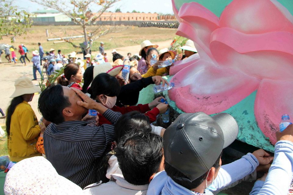 Tưới nước mang theo lên tòa sen dưới chân Phật Bà Nam Hải tại khu Quán Âm Phật Đài, thành phố Bạc Liêu, tỉnh Bạc Liêu. (Ảnh: Thanh Liêm/TTXVN)
