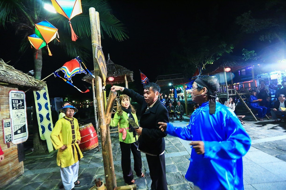 Du khách tham gia rút thẻ bài hô hát khi thưởng lãm nghệ thuật Bài Chòi ở phố cổ Hội An. (Ảnh: Trọng Đạt/TTXVN)