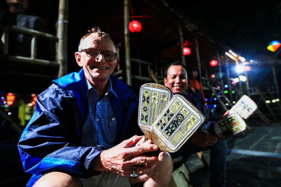 Du khách nước ngoài thích thú khi được ngồi xem và tham gia vào một buổi diễn xướng nghệ thuật Bài Chòi ở phố cổ Hội An. (Ảnh: Trọng Đạt/TTXVN)