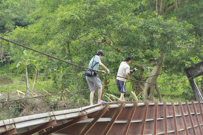 Việc đi vào thôn Lũng Cáng trên chiếc cầu treo bị lũ cuốn, hư hỏng nặng giờ hết sức khó khăn, nguy hiểm. (Ảnh: TTXVN phát)