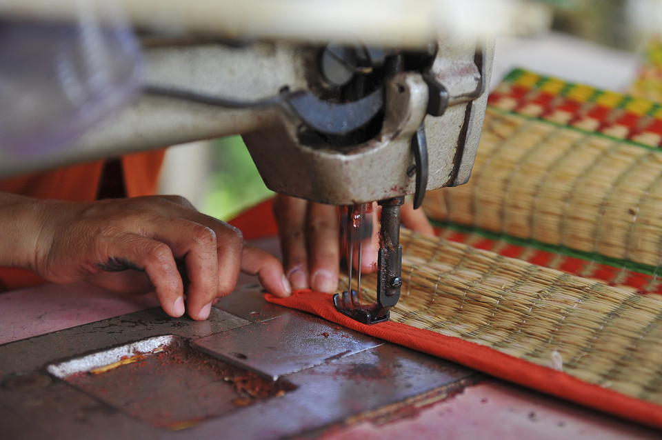 May bìa chiếu là công đoạn cuối cùng để hoàn thiện một chiếc chiếu hoàn chỉnh. (Ảnh: Minh Đức/TTXVN)