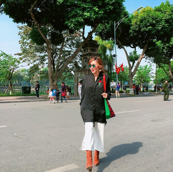 VJ Kaylee biến tấu ấn tượng quần culottes trắng xẻ vạt bằng cách mix mẫu quần này cùng sơ mi đen thêu hoa, kết hợp phụ kiện boots da lộn cao cổ và túi tote màu sắc bắt mắt.