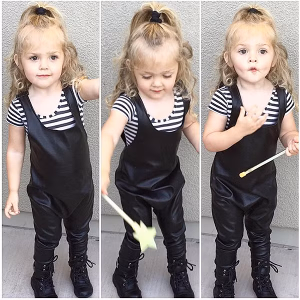 Daisy Lou xinh như búp bê với mái tóc vàng xoăn nhẹ buộc chỏm cao khi điệu đà với bộ jumpsuit (bộ đồ liền) màu đen giả da.