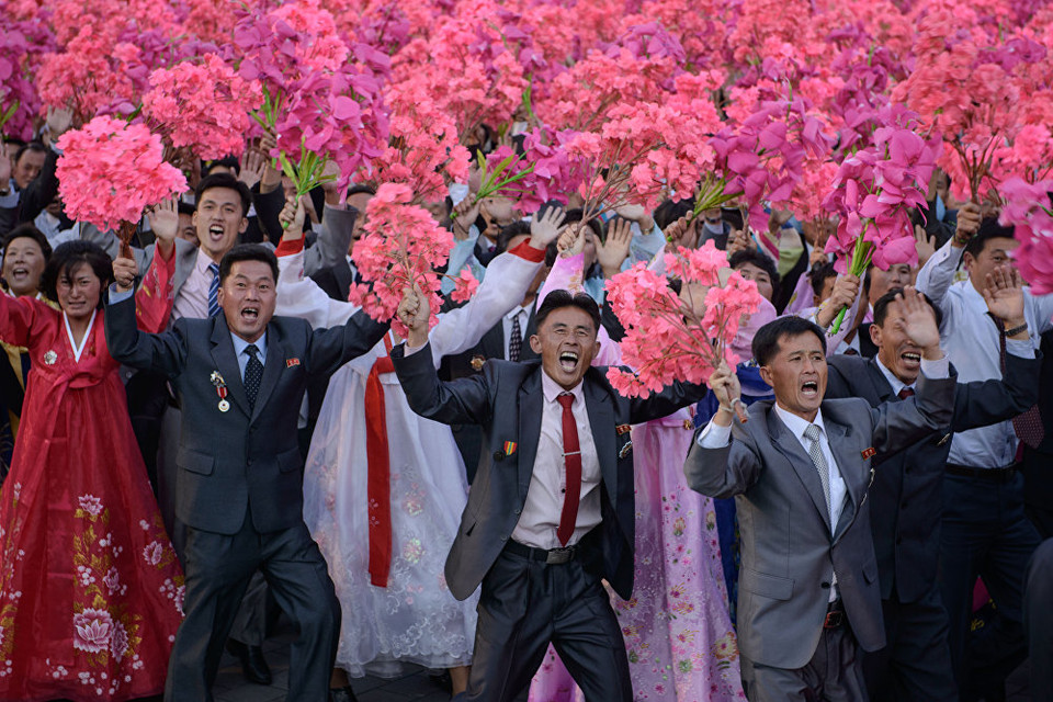 Những người tham gia vẫy hoa khi họ đi qua quảng trường Kim Nhật Thành. (Nguồn: Sputniknews)