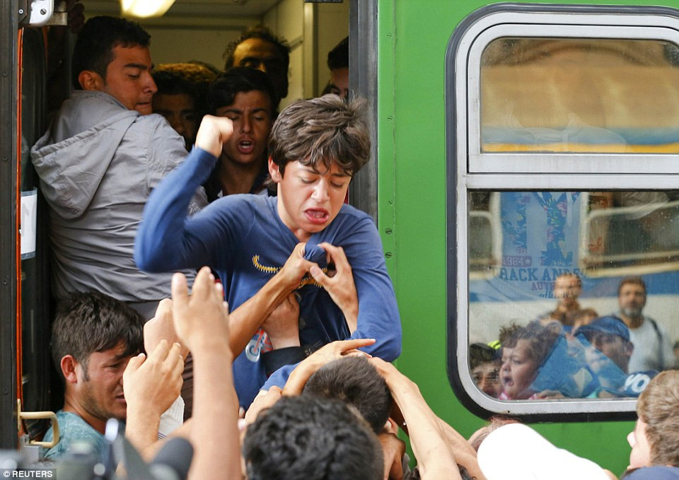 Một thanh niên đang đấm vào những người tị nạn cố kéo cậu xuống tàu. (Nguồn: Dailymail)