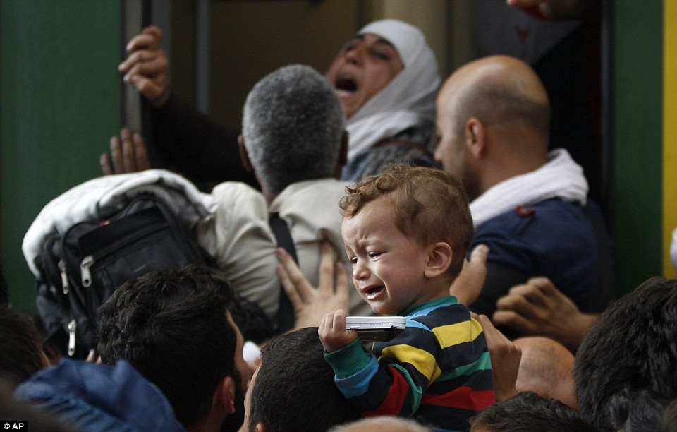 Một em bé khóc giữa hàng trăm người cố leo lên tàu. (Nguồn: Dailymail)