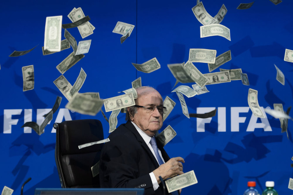 Chủ tịch FIFA Sepp Blatter bẽ bàng khi bị một 'kẻ quá khích' ném tập tiền giả vào mặt ngay trong buổi họp báo bất thường của FIFA tại trụ sở chính ở Zurich (Thụy Sỹ), ngày 20/7. (Nguồn: AFP)