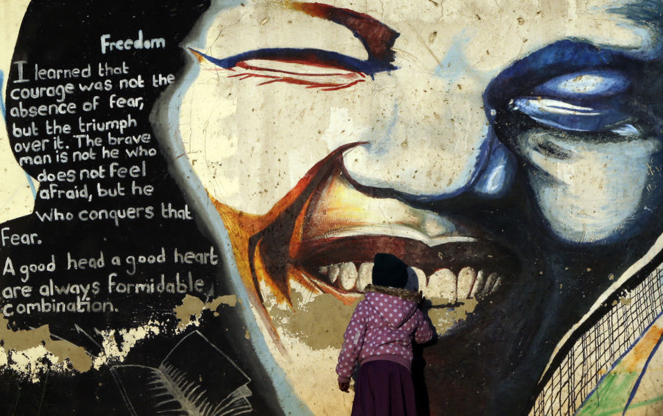 Một cô gái trẻ có tên là Thando Masuku, hôn một bức tranh tường vẽ khuôn mặt của cựu Tổng thống Nam Phi Nelson Mandela tại thị trấn Katlehong, Nam Phi. (Nguồn: AP)