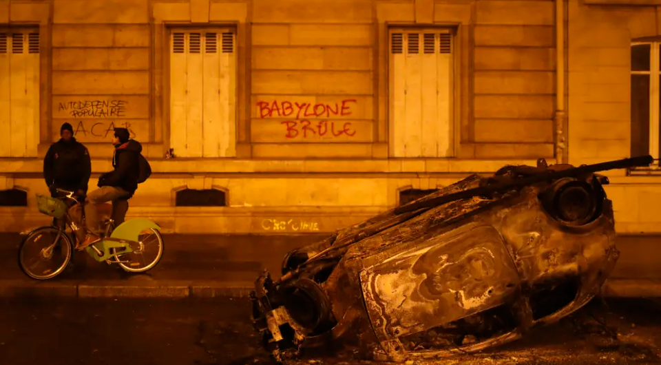 Một chiếc xe bị đốt cháy và khẩu hiệu, "đốt cháy Babylon" ở Paris vào rạng sáng 2/12. (Nguồn: AP)